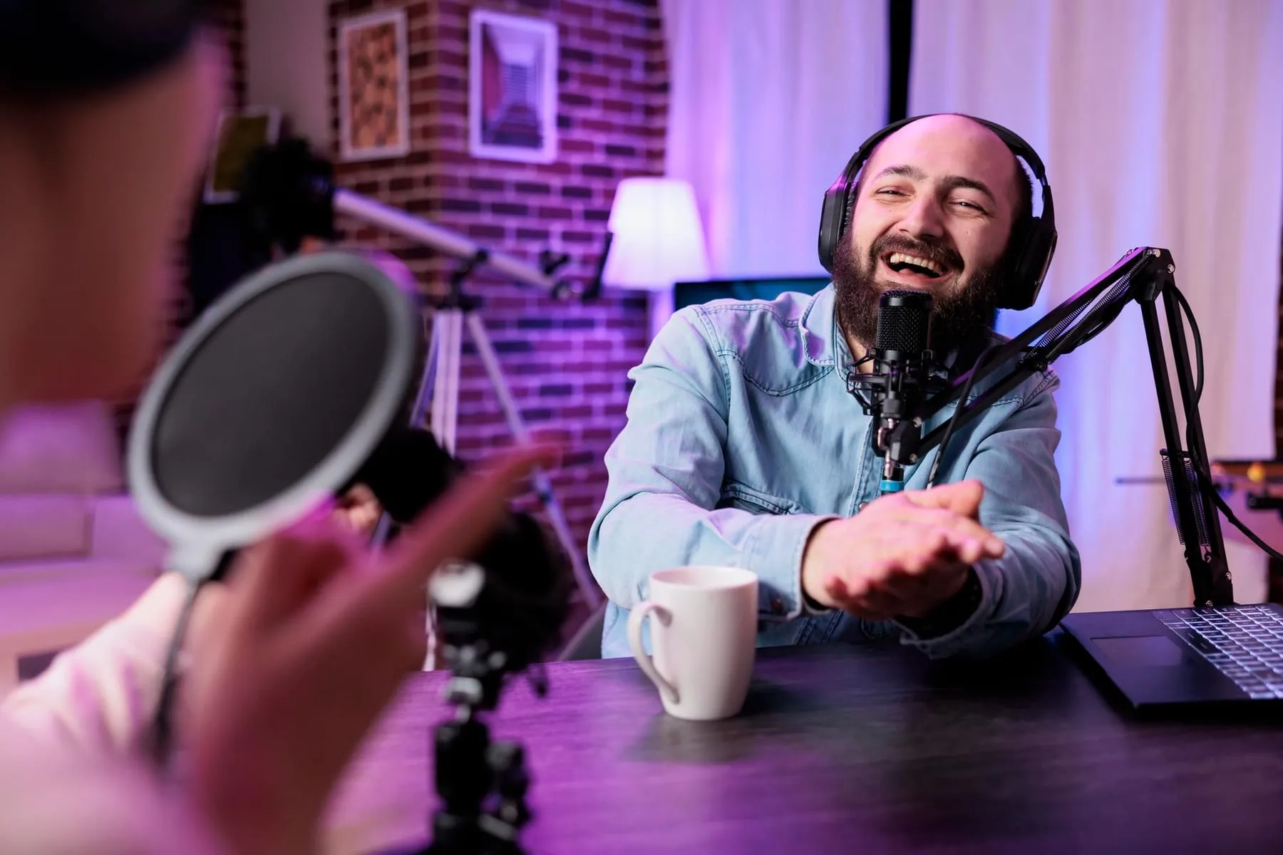Homem sorrindo diante do microfone em um estúdio de rádio