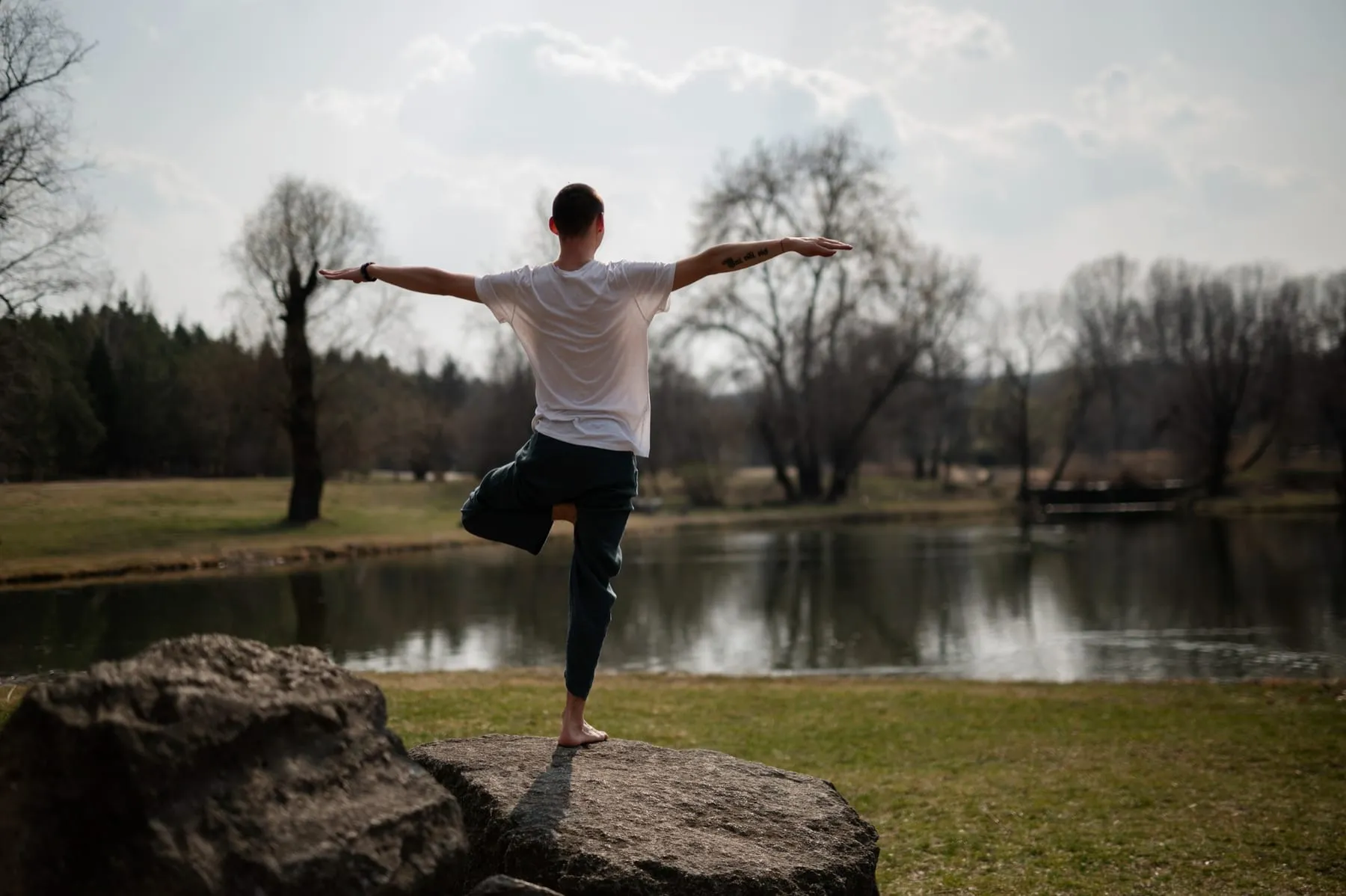 Pessoa se equilibrando em um parque, de frente para o lago